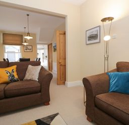 A living room with two brown sofas with cushions and a floor lamp at Derwent Cottage in Keswick