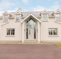 A two-story house with multiple windows a central entrance and a paved driveway at Hazelwood in Leap County Cork