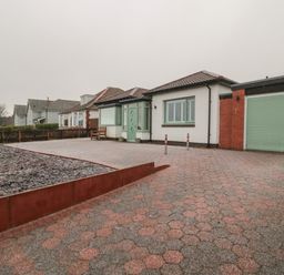 Exterior view of a one-story house with a tiled roof green door and garage with patterned driveway Bamburgh Dunes Bamburgh near Seahouses