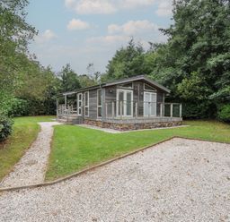 A house with a deck and pathway surrounded by grass and trees at 3 Southern Place in Dobwalls