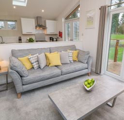 A living room with a sofa with cushions a coffee table with a bowl of green apples and a side table lamp at 4 Faraway Fields Dobwalls