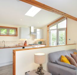 A living room with a kitchen area and a sofa at 5 Faraway Fields in Dobwalls