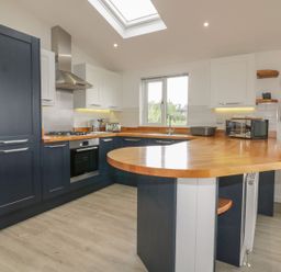 A kitchen with dark blue and white cabinets wooden countertops and a skylight at 7 Faraway Fields in Dobwalls
