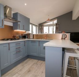 A kitchen with blue cabinets and copper accents including a faucet knife holder and kettle at 19 Meadow Retreat in Dobwalls