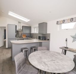 A kitchen with grey cabinets and counters a round dining table with chairs and a small table against the wall with a star decoration at 1 Southern Place in Dobwalls