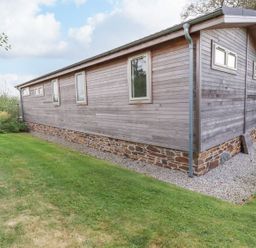 An exterior view of a wooden house with stone foundation and grass lawn at 15 Faraway Fields in Dobwalls