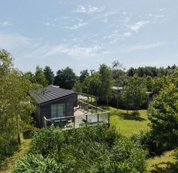 A house with a deck surrounded by trees and grass at 11 Meadow Retreat in Dobwalls