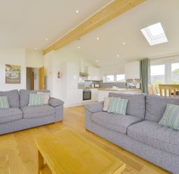 A living room with two gray sofas a wooden coffee table an open kitchen with white cabinets and a dining area at 4 Horizon View in Dobwalls