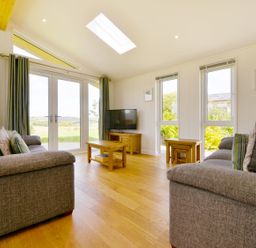A living room with two grey sofas a wooden coffee table a television and large windows at 4 Horizon View in Dobwalls