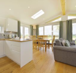 An open kitchen and dining area with wooden dining table and chairs and a grey sofa at 4 Horizon View in Dobwalls