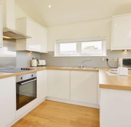 A kitchen with white cabinets wooden countertops a built in oven a toaster a kettle a microwave and a window at 4 Horizon View in Dobwalls