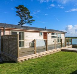 A wooden single-story house with a deck and glass railings overlooking a grassy yard at 14 Faraway Fields in Dobwalls