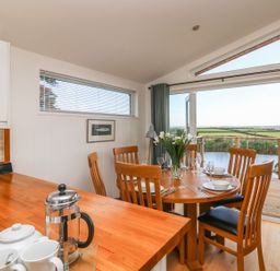 A dining area with a round wooden table set for a meal and wooden chairs with an outdoor view at 14 Faraway Fields in Dobwalls
