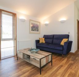 A living room with a blue sofa a wooden coffee table and wall-mounted lights at 9 Meadow Retreat in Dobwalls