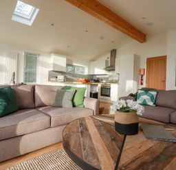 A living room with two sofas green cushions a wooden table and a kitchen in the background at 14 Horizon View in Dobwalls