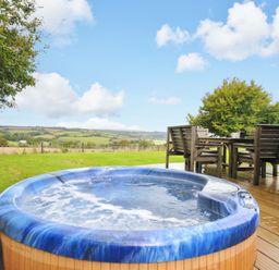 A hot tub on a wooden deck with a table and chairs at 8 Horizon View in Dobwalls