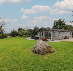 A house with outdoor furniture on a lawn with a large rock in front at 9 Horizon View in Dobwalls