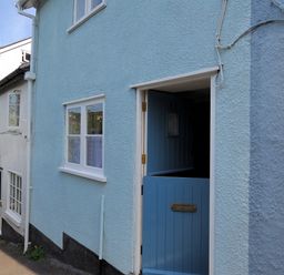 A street view of houses with a blue half door open at 30 Sherborne Lane Lyme Regis