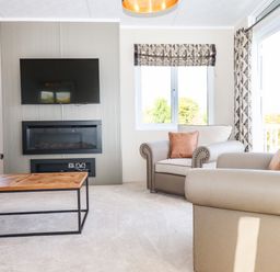 A living room with armchairs a coffee table a wall mounted TV and an electric fireplace at Chestnut Lodge in Teigngrace near Newton Abbot