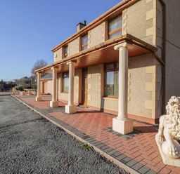 Exterior of a house with columns and lion statues on a paved area at Bryn Berthen in Penrhyndeudraeth