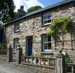 Stone house with blue door and windows and a small front garden with a stone fence at Delfryn Newport
