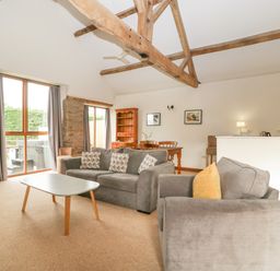 A living room with sofas coffee table dining table and kitchen area at Peartree Cottage in Stanford Bishop near Bromyard