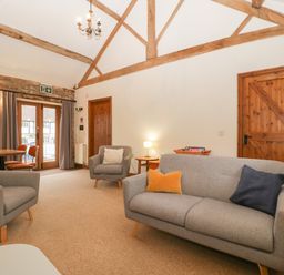 A living room with gray sofas wooden doors and exposed wooden beams at Clover Patch Cottage in Stanford Bishop near Bromyard