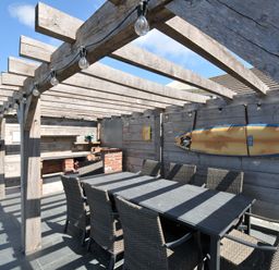 An outdoor dining area with a table and chairs under a pergola at Breakers View in Polzeath