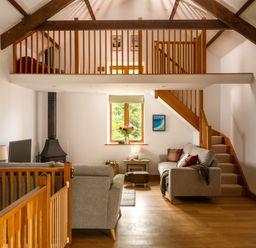A living room with a staircase and window at Hoppers Barn Pancrasweek near Holsworthy