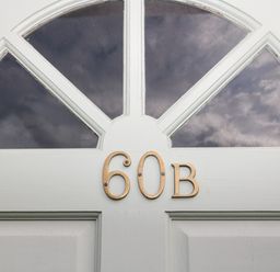 A white door with brass house numbers 60B and arched glass panels at 60B Castlegate in Berwick-Upon-Tweed