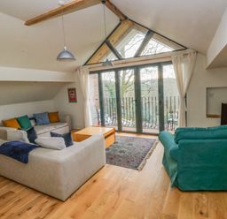 A living room with sofas a coffee table a rug and a television near large windows with curtains at Green Grove Barn in Peniel near Carmarthen
