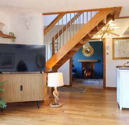 A living room with a television on a stand and a staircase at Hillsview in Combe Martin