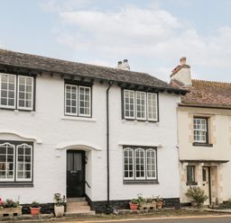 A street view of two adjoining houses with multiple windows and flower pots at The Pound in Porlock