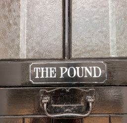 A close up of a black door with a handle and a sign that says The Pound at The Pound in Porlock