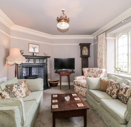 A living room with two light green sofas floral armchair wooden coffee table television and a fireplace at The Pound in Porlock