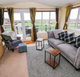 A living room with a sofa and armchair at Reef Retreat in Little Haven