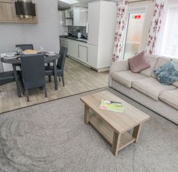 A living room with a sofa and coffee table next to a dining table and kitchen at Seahorse Retreat in Little Haven near Broad Haven