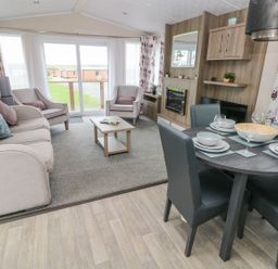 A living room with sofa chairs coffee table and dining table set at Seahorse Retreat Little Haven near Broad Haven