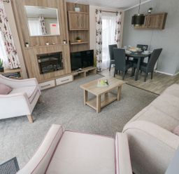 A living room with chairs a sofa coffee table dining table and TV at Seahorse Retreat in Little Haven near Broad Haven