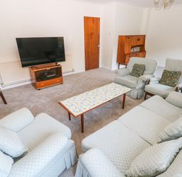A living room with armchairs sofa coffee table television and wooden cabinet at 30 Long Shepherds Drive in Newton near The Mumbles