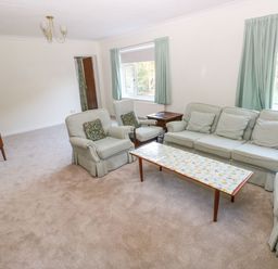 A living room with pastel upholstered sofa and armchairs a wooden coffee table and side table at 30 Long Shepherds Drive in Newton near The Mumbles