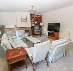 A living room with a sofa set a coffee table a wooden side table a television on a stand a bookshelf and an armchair at 30 Long Shepherds Drive Newton near The Mumbles