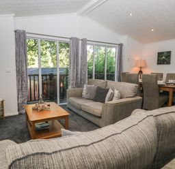 A living room with a sofa, tv, and dining area at Treetops, Beech Hill 13, Fallbarrow Park near Bowness-On-Windermere