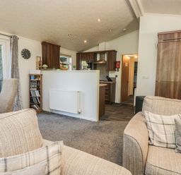 A living room with a sofa and kitchen area at Treetops Beech Hill 13 ,Fallbarrow Park near Bowness-On-Windermere