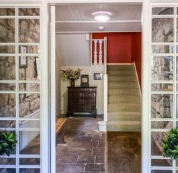A stone entry hallway with carpeted stairs wooden chest and floral arrangement at Craster Tower Penthouse in Craster