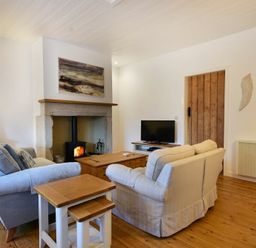A living room with sofas a fireplace a television and wooden furniture at Periwinkle in Bamburgh