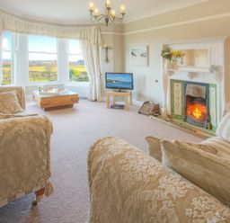 A living room with patterned sofas a fireplace a television and a window with a view at The Villas No3 in Embleton