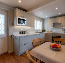 A kitchen with wooden chairs a table with fruit and cabinets at Castle View Bamburgh