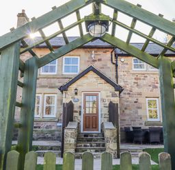 An outdoor view of a house with an archway and seating area at Bramley in Lucker