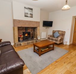 A living room with a fireplace and sofa at Bramley in Lucker
